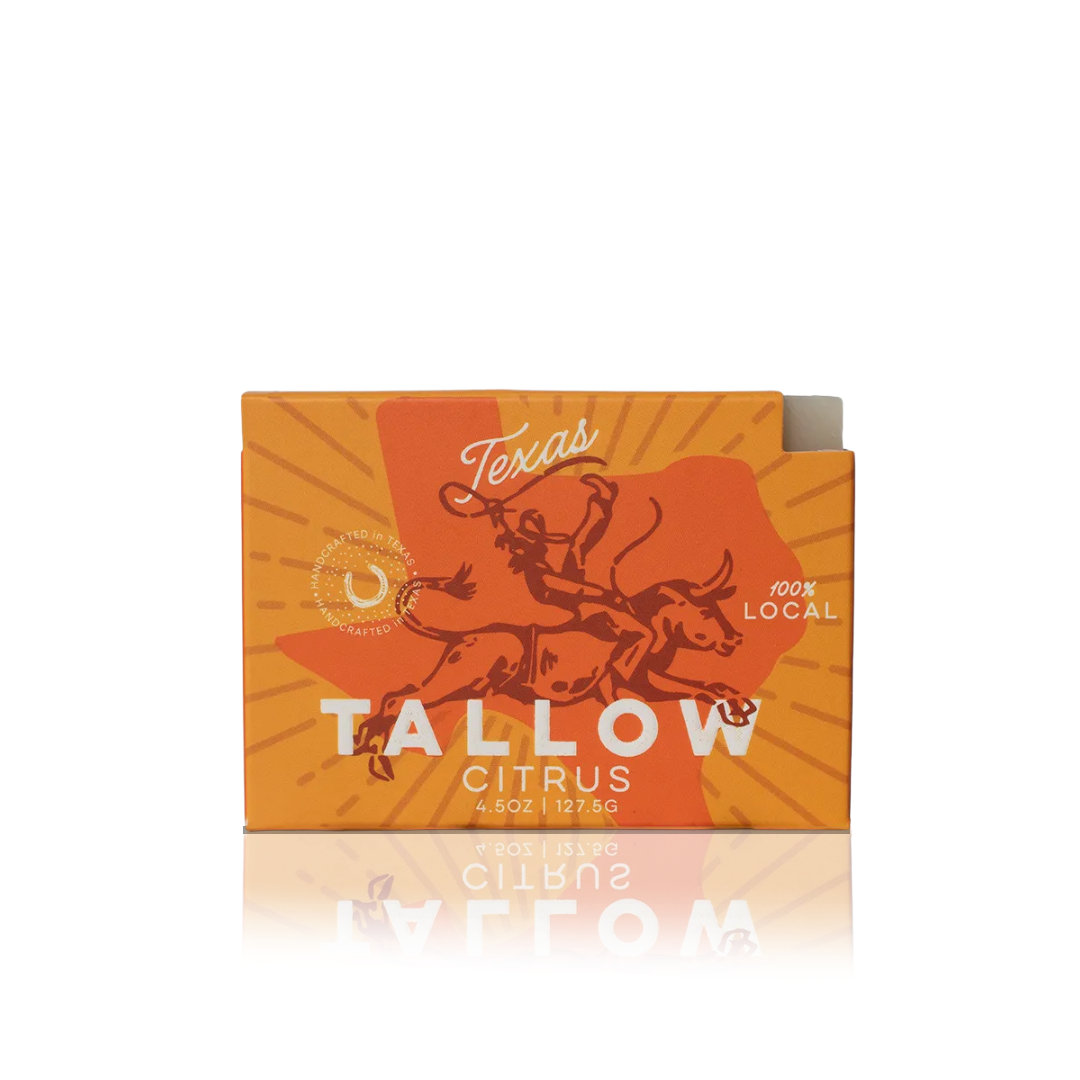 A packaged bar soap with orange and yellow packaging, featuring an illustration of a bull and the text 'Texas Tallow Citrus Bar Soap 100% Local'.